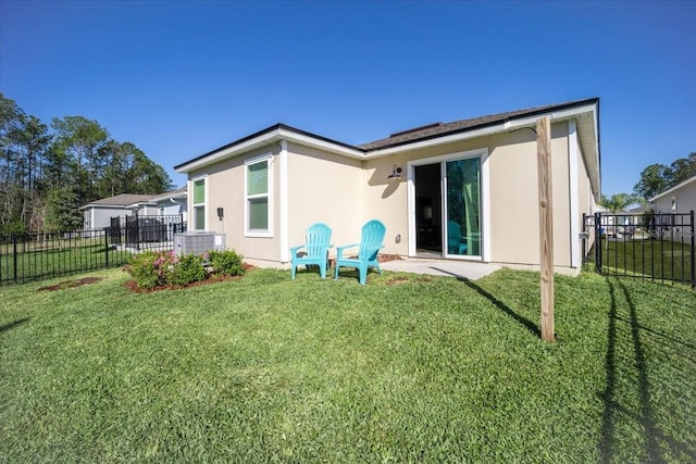 back of property with stucco siding, a yard, and fence