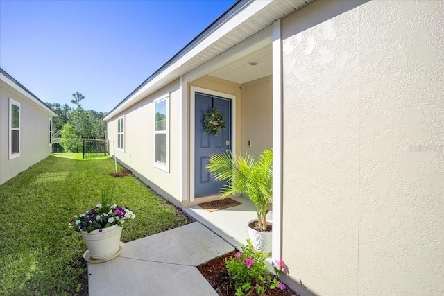 property entrance with stucco siding and a lawn