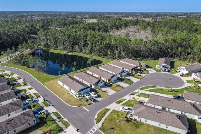 drone / aerial view featuring a view of trees, a water view, and a residential view