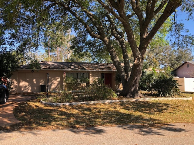 view of front facade featuring stucco siding, driveway, an attached garage, and fence