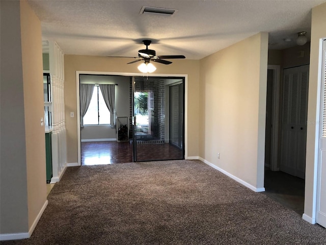 carpeted spare room featuring visible vents, ceiling fan, a textured ceiling, and baseboards