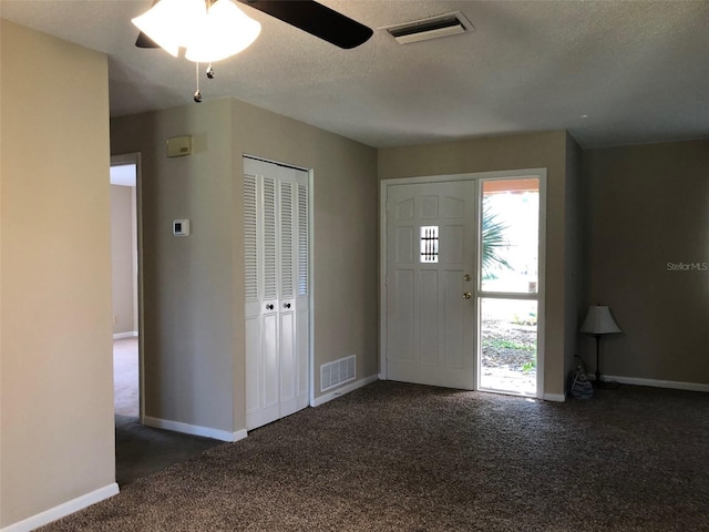 entryway featuring visible vents, a textured ceiling, baseboards, and carpet floors