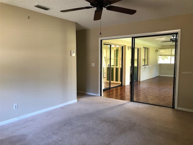 carpeted empty room featuring visible vents, a textured ceiling, and baseboards