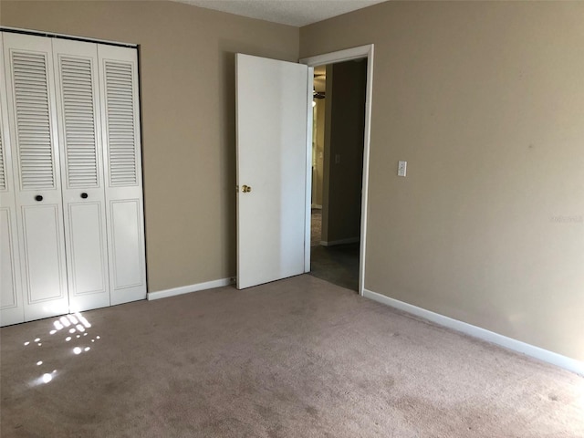 unfurnished bedroom featuring baseboards, carpet floors, and a closet