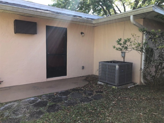 entrance to property with a patio area, stucco siding, and cooling unit