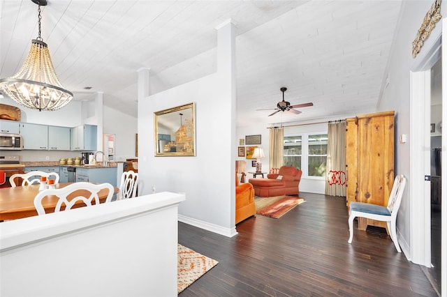 interior space with baseboards, lofted ceiling, dark wood-style flooring, and ceiling fan with notable chandelier