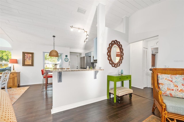 kitchen featuring visible vents, freestanding refrigerator, a peninsula, a breakfast bar area, and dark wood-style flooring