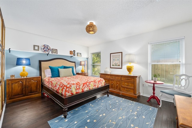 bedroom featuring dark wood finished floors, baseboards, and a textured ceiling