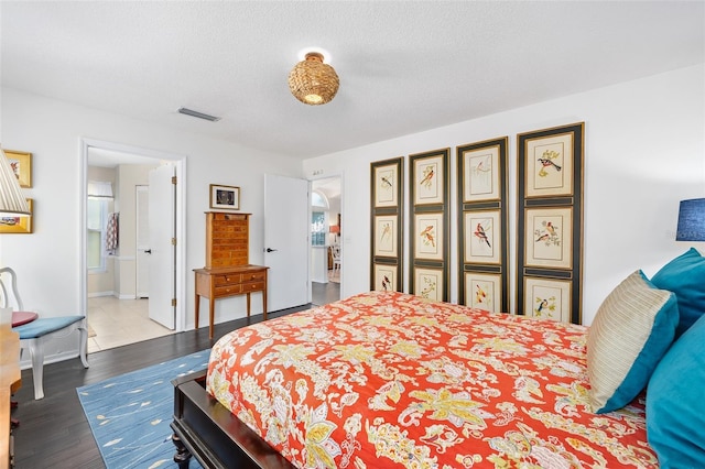 bedroom featuring visible vents, baseboards, a textured ceiling, and wood finished floors