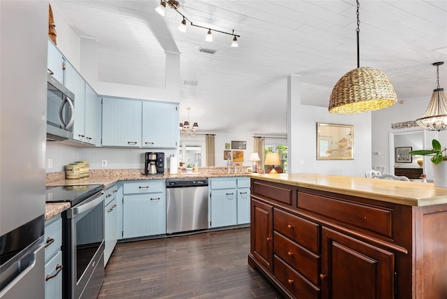 kitchen with dark wood-style floors, a peninsula, stainless steel appliances, light countertops, and decorative light fixtures