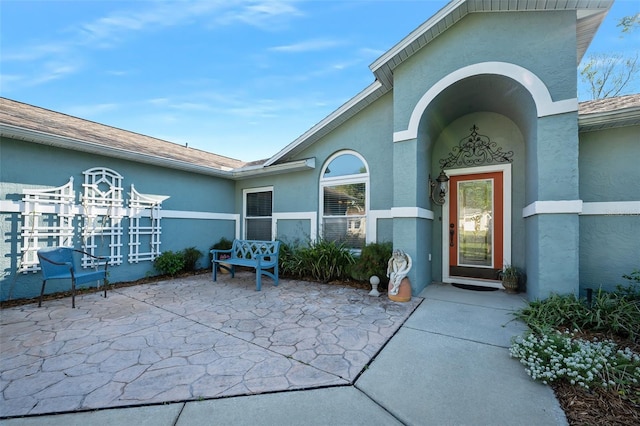 property entrance featuring stucco siding and a patio