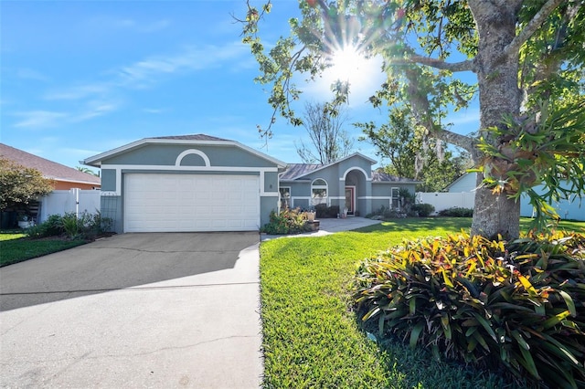 ranch-style house featuring concrete driveway, an attached garage, fence, and stucco siding