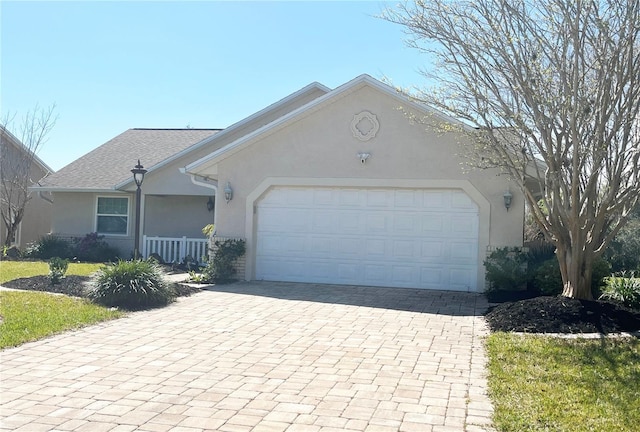 ranch-style home featuring stucco siding, decorative driveway, and a garage