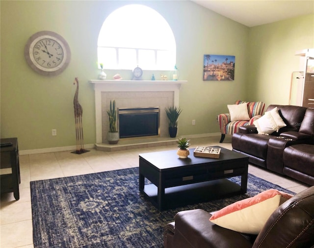 living area with tile patterned flooring, a tiled fireplace, and baseboards