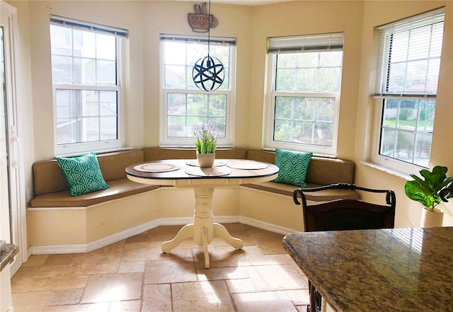 dining room with breakfast area, baseboards, stone tile floors, and a healthy amount of sunlight