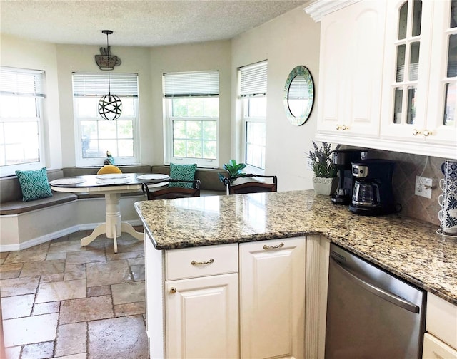 kitchen with a peninsula, stone tile flooring, white cabinets, dishwasher, and breakfast area