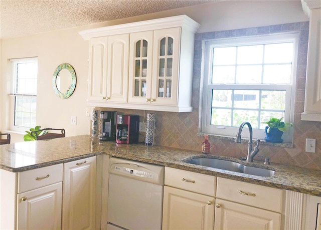 kitchen with a peninsula, plenty of natural light, white dishwasher, and a sink