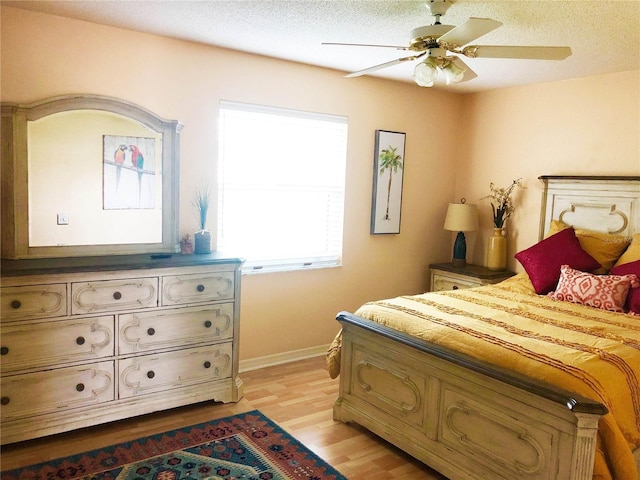 bedroom with light wood-type flooring, baseboards, a textured ceiling, and ceiling fan