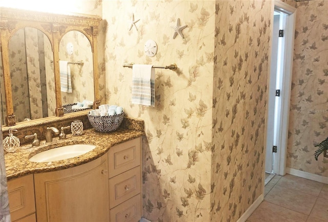 bathroom with wallpapered walls, tile patterned floors, vanity, and baseboards