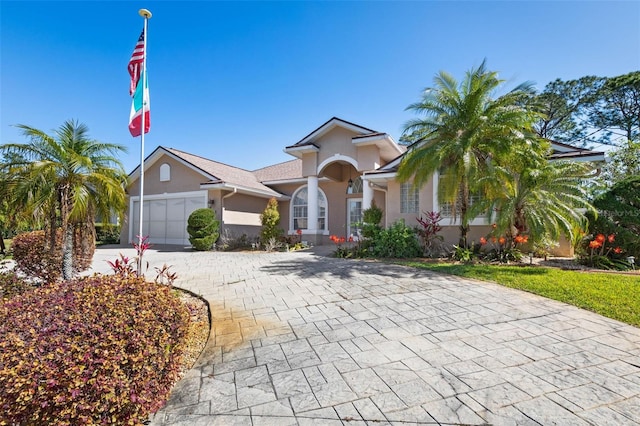 view of front of property featuring decorative driveway, a garage, and stucco siding