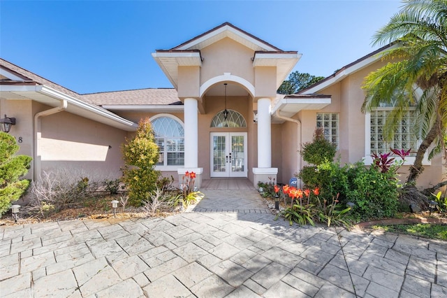 view of exterior entry featuring stucco siding and french doors