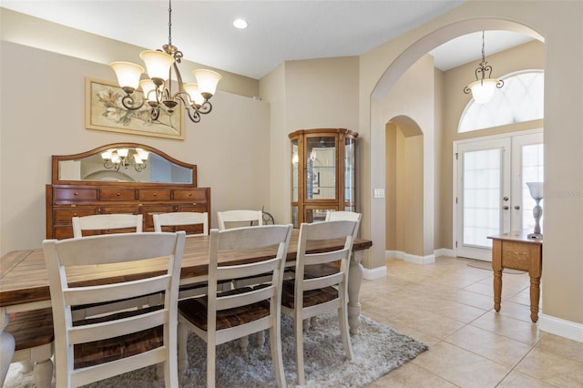 dining room with baseboards, arched walkways, a chandelier, and light tile patterned flooring