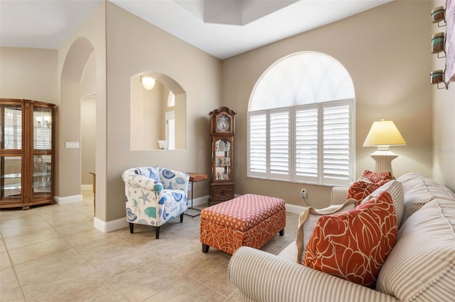 tiled living area with arched walkways and baseboards