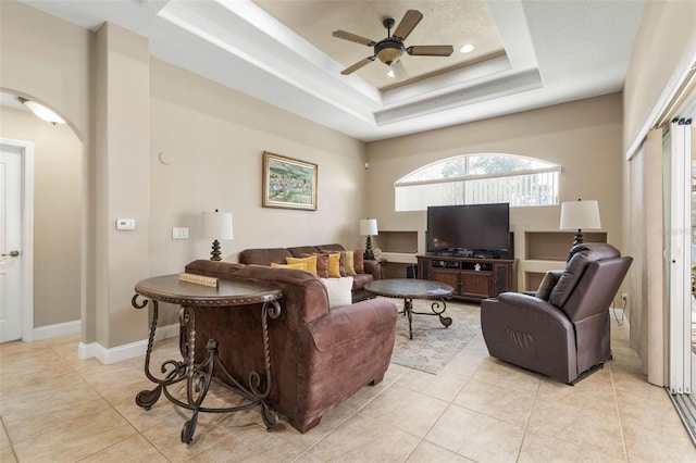 living room featuring light tile patterned floors, baseboards, a raised ceiling, and ceiling fan