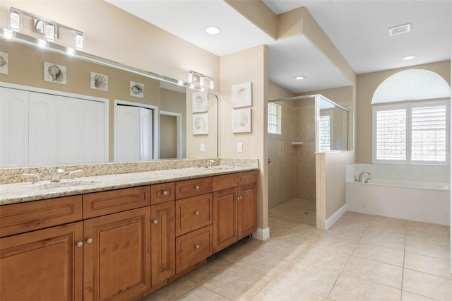 full bathroom with tile patterned floors, visible vents, a sink, a tile shower, and double vanity