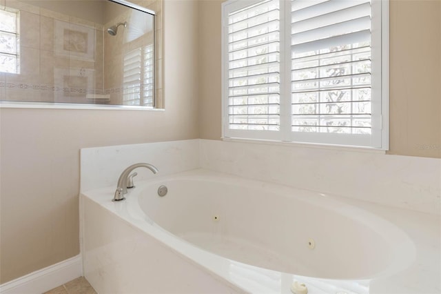 full bathroom with tile patterned flooring, plenty of natural light, a whirlpool tub, and tiled shower