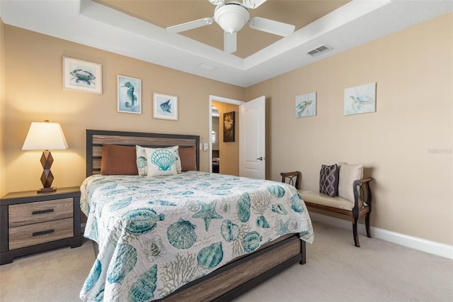 bedroom with visible vents, baseboards, light colored carpet, a tray ceiling, and a ceiling fan