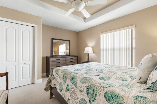 bedroom featuring baseboards, ceiling fan, a closet, a raised ceiling, and carpet flooring