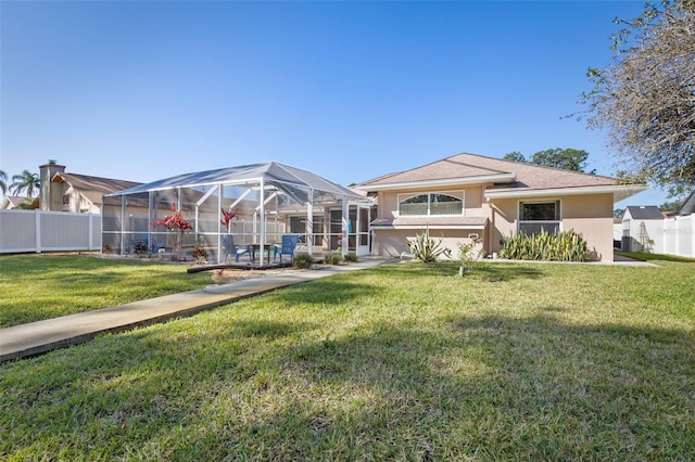 rear view of house featuring a lanai, a fenced backyard, a lawn, and stucco siding