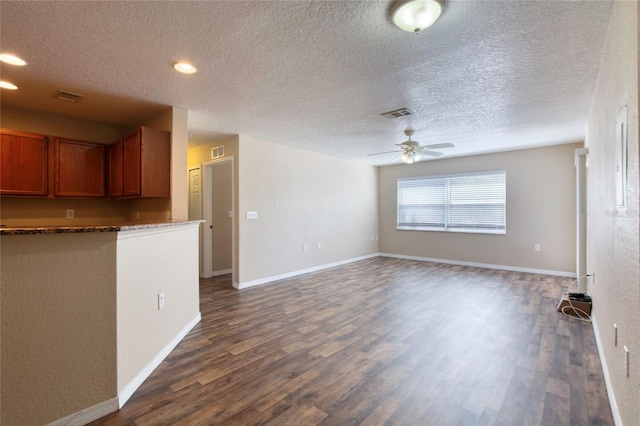 unfurnished living room featuring visible vents, baseboards, dark wood-style floors, and a ceiling fan