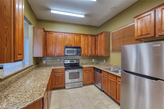 kitchen with light tile patterned flooring, brown cabinetry, and appliances with stainless steel finishes