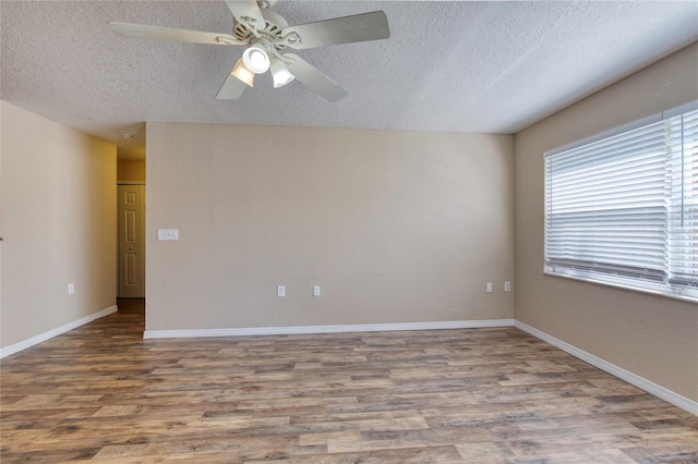 spare room featuring baseboards, wood finished floors, a textured ceiling, and ceiling fan