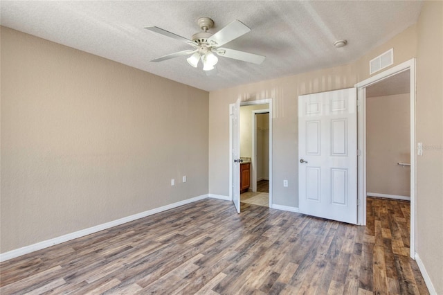 unfurnished bedroom with wood finished floors, visible vents, baseboards, ceiling fan, and a closet