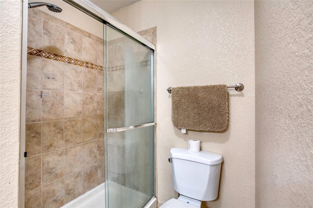 full bath with toilet, a textured wall, and tiled shower