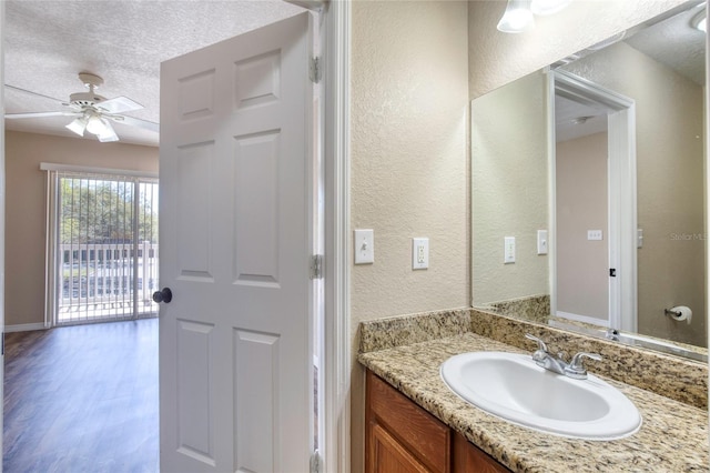 bathroom featuring ceiling fan, vanity, a textured wall, wood finished floors, and a textured ceiling