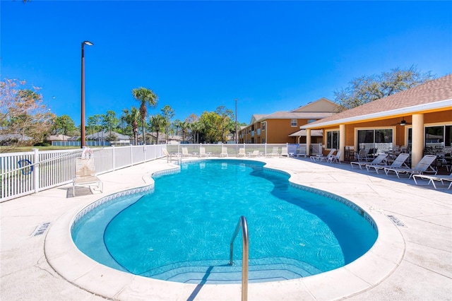 community pool with fence, a ceiling fan, and a patio area