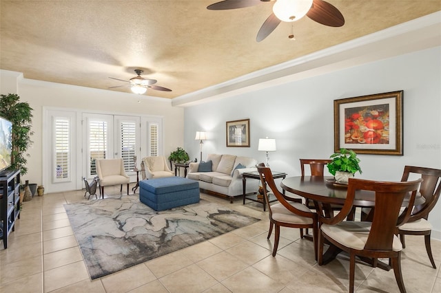 living area with a raised ceiling, light tile patterned floors, a ceiling fan, and a textured ceiling