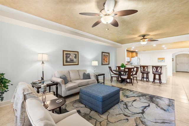 living room with baseboards, ceiling fan, light tile patterned floors, recessed lighting, and arched walkways