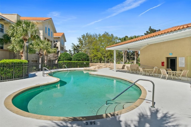 community pool with a patio and fence