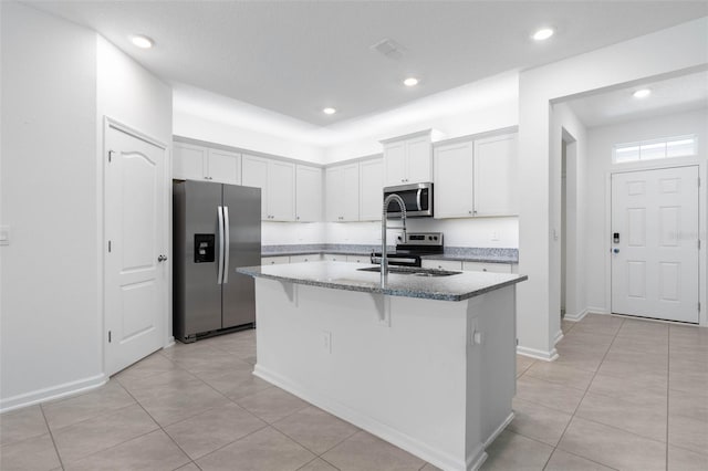 kitchen featuring light stone countertops, appliances with stainless steel finishes, an island with sink, and white cabinetry