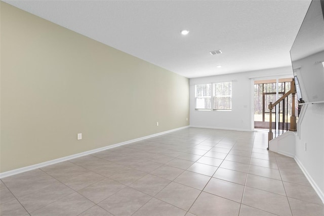 spare room with stairs, light tile patterned flooring, baseboards, and visible vents