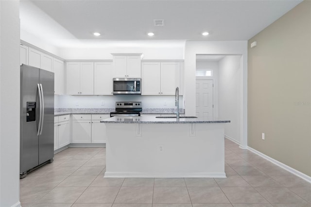 kitchen with visible vents, light stone counters, stainless steel appliances, white cabinetry, and a sink