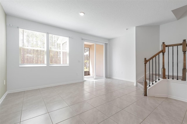 unfurnished room with baseboards, a textured ceiling, and light tile patterned flooring