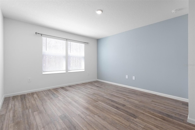 spare room with wood finished floors, baseboards, and a textured ceiling