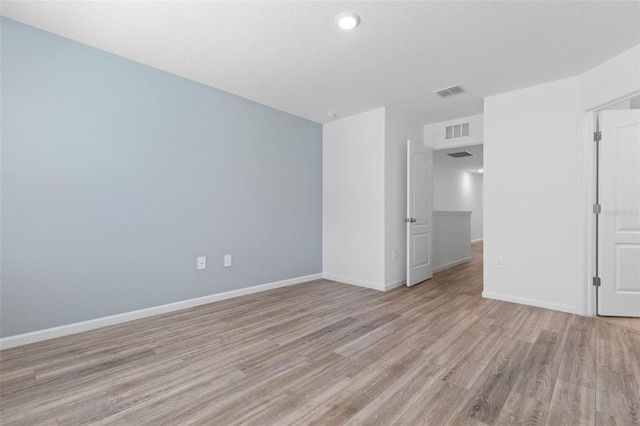 empty room featuring light wood finished floors, visible vents, and baseboards