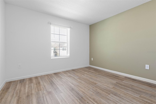 empty room with baseboards and light wood-style flooring